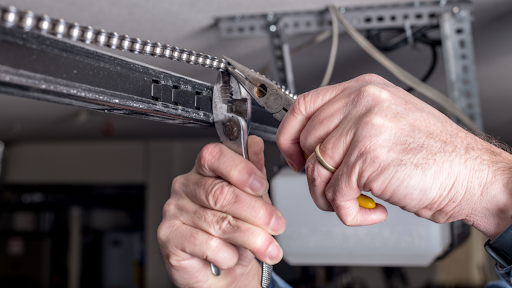 Technician making preventive garage door repairs
